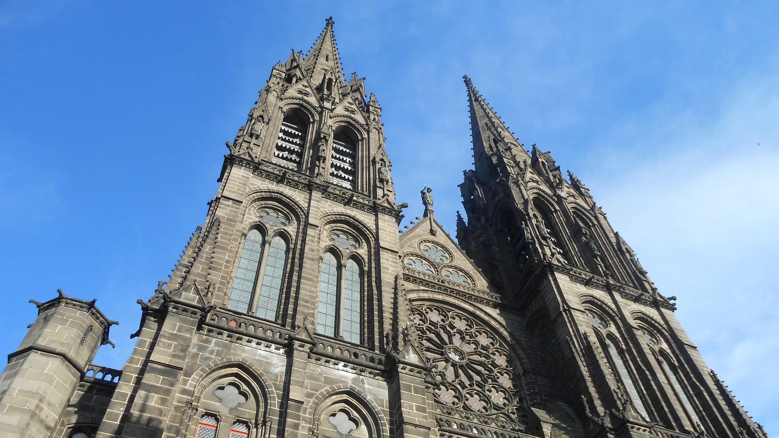 Les deux flèches et la rosace de la cathédrale de Clermont-Ferrand en pierre de Volvic, vues en contre-plongée sur ciel bleu