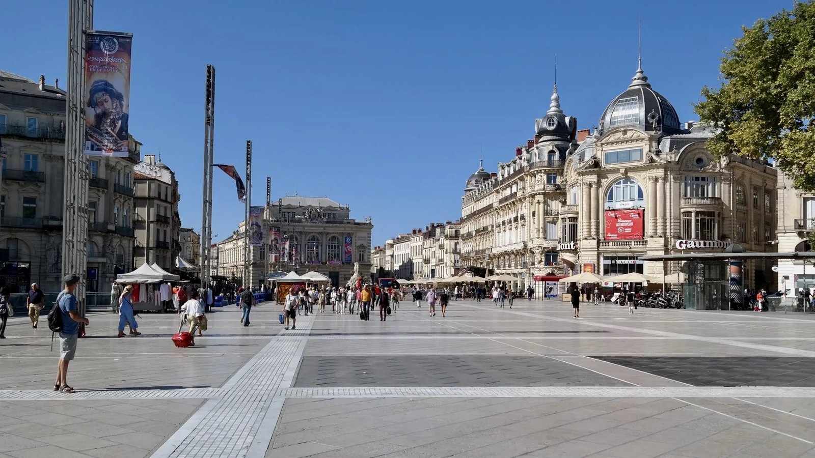 La place de la Comédie à Montpellier, vaste et ensoleillée, l’Opéra au fond et les passants sur le dallage clair